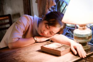 sleeping woman in front of turned on table lamp beside books